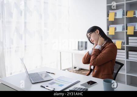 una donna d'affari pianifica un audit finanziario, rivedendo i documenti mentre combatte la sindrome da burnout Foto Stock