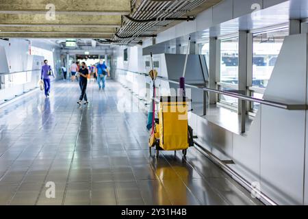 Pulizia delle attrezzature della governante tramite mob, bidoni, salviette e scope nella hall dell'aeroporto con sfondo sfocato. Foto Stock