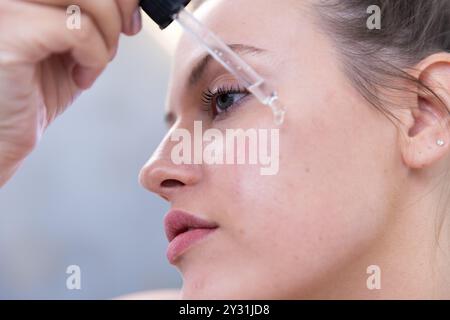 Primo piano, a casa, applicando siero facciale, donna che si concentra sulla routine della cura della pelle Foto Stock