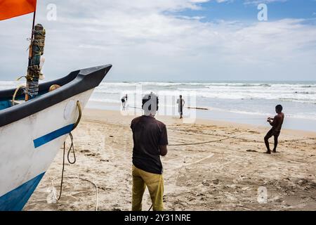 Gruppo di pescatori rurali che tirano reti da pesca dal mare a Goa Arambol. Pesca in spiaggia a Goa, India. Pesca tradizionale di Goan. Industria della pesca Foto Stock