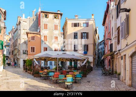 Un vivace caffè all'aperto a Rovigno invita i clienti a godersi vivaci posti a sedere sotto una spaziosa tettoia. Le affascinanti strade di questa città costiera si crogiolano nel cuore Foto Stock