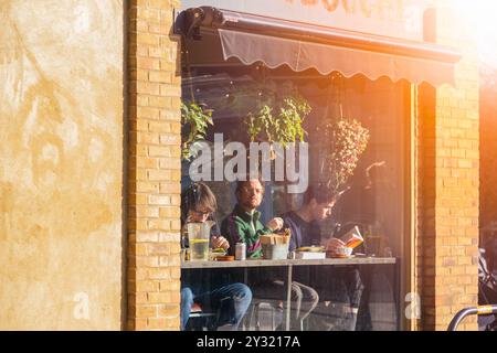 Londra, Regno Unito - 25 gennaio 2023 - clienti in una caffetteria al Broadway Market, London Field. Forte bagliore solare. Foto Stock