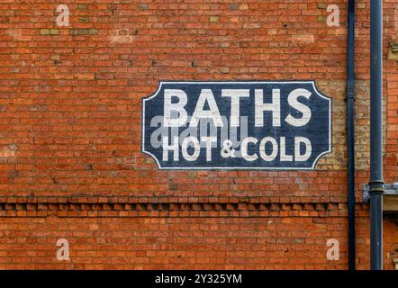 Vittoriano? Insegna fantasma dipinta su un muro di mattoni a Banbury che pubblicizza Baths Hot & Cold. Sparato da High Street, Banbury. Foto Stock