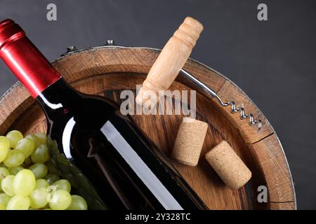 Cavatappi, bottiglia di vino, uva, sughero e botte di legno su tavolo grigio, vista dall'alto Foto Stock