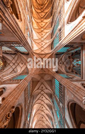 La luce del sole splende attraverso vetrate colorate che illuminano il soffitto a volta della cattedrale gotica medievale di San Vito. Praga, Repubblica Ceca Foto Stock