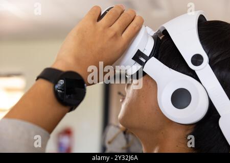 Utilizzando il visore VR, adolescente asiatico che esplora l'esperienza di realtà virtuale in ambiente scolastico Foto Stock