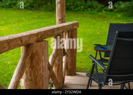 Balcone in legno con telefono cellulare appoggiato su un tavolo nero accanto alle sedie nella foresta ceca in tarda estate Foto Stock