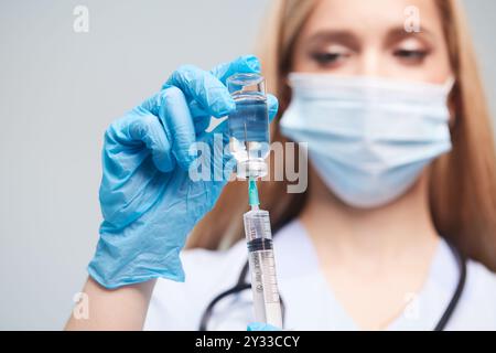 Operatore sanitario che prepara il vaccino, medico che disegna la medicina in siringa primo piano su sfondo bianco, concetto di vaccino Foto Stock