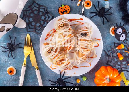 Cibo divertente per bambini per il pranzo o la cena di Halloween. Spaghetti con salsicce, ricetta creativa sotto forma di mummie con ketchup fatto di sangue, con Hallowe Foto Stock