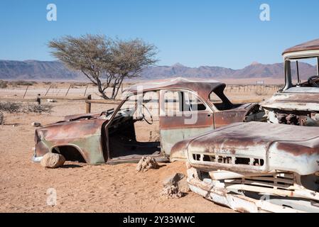 Arrugginito relitto d'auto d'epoca abbandonato nel remoto insediamento di Solitaire, Namibia, circondato da un paesaggio desertico africano Foto Stock