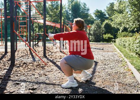 Una donna allegra e di grandi dimensioni si esercita all'aperto in un parco vivace. Foto Stock