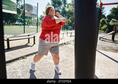 Una donna sicura di sé si esercita all'aperto in un parco vivace. Foto Stock