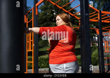 Una donna di grandi dimensioni si esercita all'aperto, abbracciando il fitness con determinazione. Foto Stock