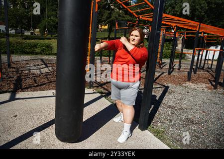 Una donna di grandi dimensioni si esercita con gioia all'aperto, godendosi l'aria fresca. Foto Stock