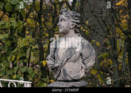 Una statua in marmo di una figura classica in un parco, circondata da alberi e fogliame. Foto Stock