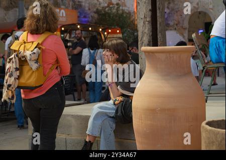 Young Woman siede con cura davanti a grandi piantagioni di terracotta in una vivace scena di mercato nel Centro culturale 8 Marvila Foto Stock