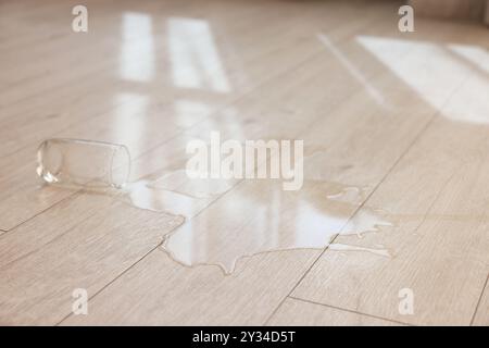 Bicchiere con bibita versata su pavimento in legno Foto Stock