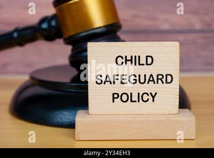 Testo della politica di salvaguardia dei bambini su blocchi di legno con sfondo martellato. Salvaguardia del concetto di politica per i minori. Foto Stock