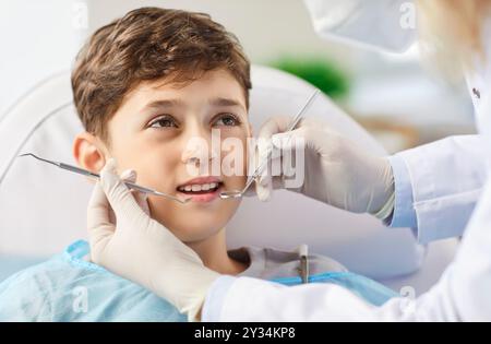 Ritrarre un bambino seduto sulla sedia del dentista facendo un esame dei denti presso la clinica di stomatologia. Foto Stock