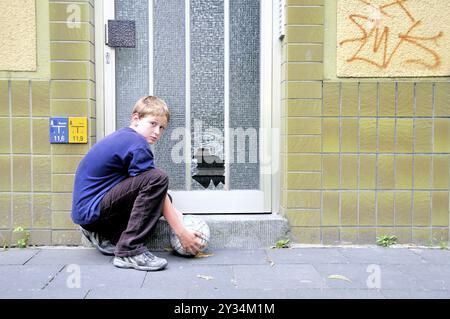Bambino di dieci anni e il vetro frantumato su una porta d'ingresso, Germania, Europa Foto Stock
