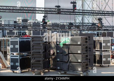 Un'ampia area è piena di custodie per attrezzature impilate e attrezzature per la preparazione di un evento imminente. Foto Stock