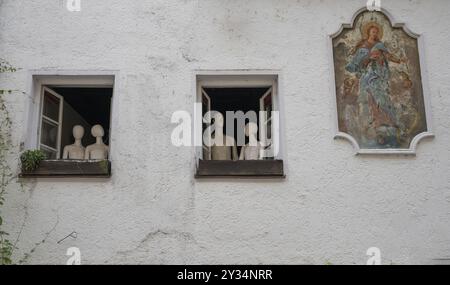 Manichini su due finestre aperte e un dipinto di un santo sulla facciata di una casa, Straubing, bassa Baviera, Germania, Europa Foto Stock