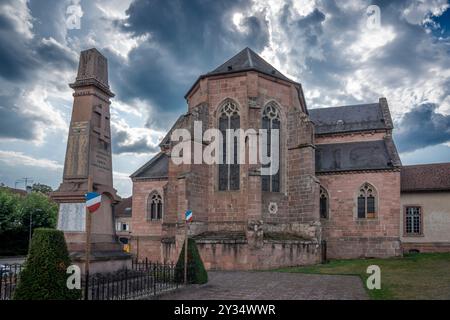 Étival-Clairefontaine, Francia - 09 01 2024: Abbazia di Saint-Pierre. Vista panoramica all'esterno del retro dell'abbazia e del monumento alla guerra Foto Stock