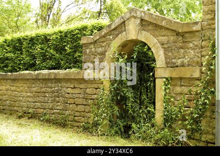 Vecchio ingresso alle pietre con un arco e una ringhiera di ferro Foto Stock