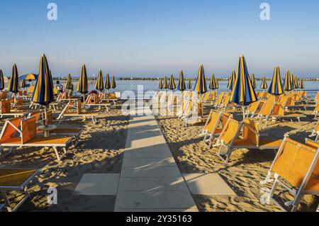 Righe di colore arancione di ombrelloni e sdraio sulla spiaggia di Igea Marina vicino a Rimini Foto Stock