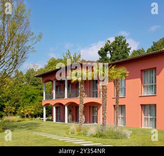 Moderna villa con patio su due livelli, c'è un grande giardino verde con palme in primo piano. Bella giornata di sole, con cielo blu. Non c'è nessuno Foto Stock