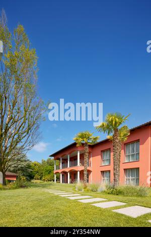 Moderna villa con patio su due livelli, c'è un grande giardino verde con palme in primo piano. Bella giornata di sole, con cielo blu. Non c'è nessuno Foto Stock