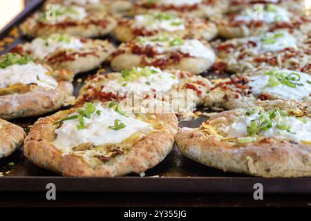 Vassoio da forno con langhi caldi freschi, focaccia ungherese variamente ripiena di funghi o pancetta e panna acida, finger food in un festival all'aperto mar Foto Stock