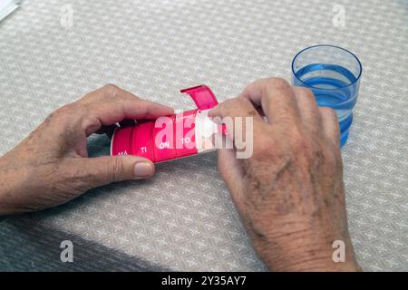 Primo piano delle donne anziane mano che prendono la medicina dalla scatola di pillole mediche, smistamento pillole. Le dosi giornaliere di una settimana di medicina sono poste in dose settimanale Foto Stock