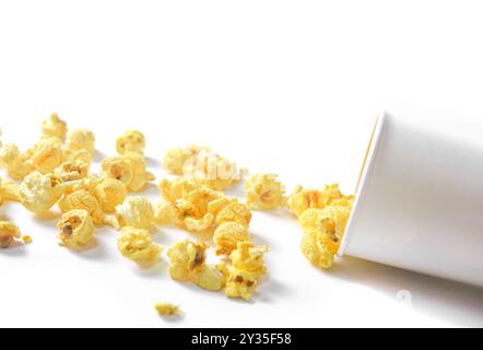 Immagine isolata di popcorn in tazza di carta su sfondo bianco, che mostra i morbidi chicchi dorati che fuoriescono sui bordi, perfetti per loro Foto Stock