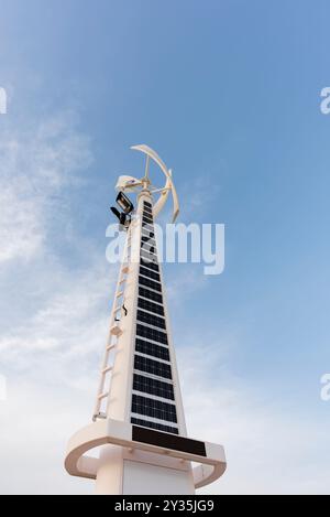 Vista verticale di un sistema ibrido di turbine solari ed eoliche in Medio Oriente, contro un cielo azzurro brillante, tecnologia avanzata per le energie rinnovabili Foto Stock