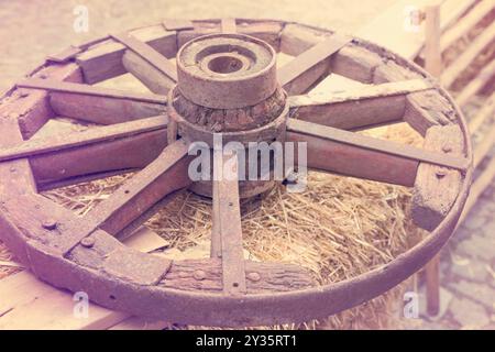 la vecchia ruota del carro in legno si trova nella mangiatoia Foto Stock