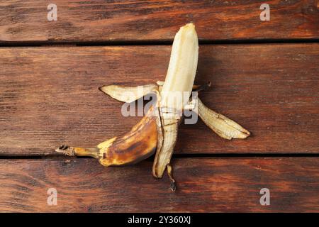 Banana troppo matura con macchie scure sul tavolo di legno, vista dall'alto Foto Stock