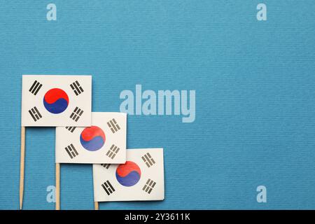 Bandierine di carta piccole della Corea del Sud su sfondo azzurro, vista dall'alto. Spazio per il testo Foto Stock