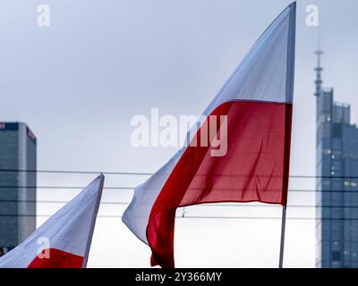 Bandiere rosse, bianche e lucide sullo sfondo con grattacieli sfocati e cielo nuvoloso. Foto Stock