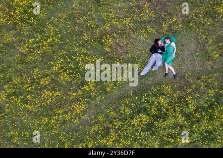 Vista dall'alto della donna che si stende su un prato in fiore. Primavera all'aperto Foto Stock