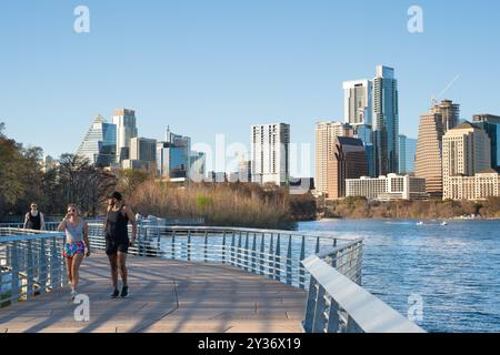 Austin, Texas - 22 febbraio 2024: Città di Austin, Texas, con persone sul percorso all'aperto lungo il fiume con edifici dello skyline sullo sfondo. Foto Stock