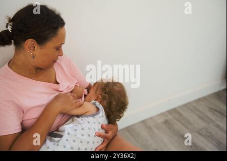 Una madre amorevole che allatta il bambino, mostrando il legame intimo e naturale. La scena trasmette comfort e calore in un ambiente sereno Foto Stock