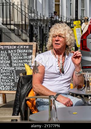 Londra, Inghilterra - 05-24-2024: Un uomo seduto in un caffè all'aperto presso lo Street Market, Portobello Road a Notting Hill, Londra, Inghilterra. Foto Stock