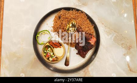 Ritratto piatto nasi kebuli (riso kebuli) al centro, tipico cibo arabo prodotto in Indonesia sul tavolo con spazio vuoto a destra e a sinistra Foto Stock