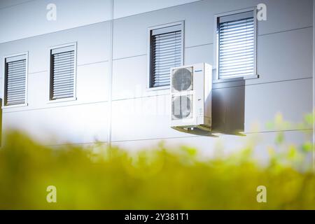 Due unità CA esterne di grado industriale con ventilatori appoggiati sulla moderna facciata metallica di un edificio industriale. Notte o sera Foto Stock