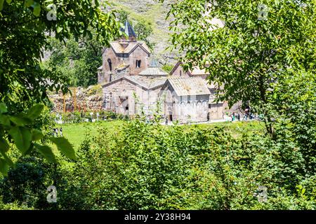 Osh, Armenia - 6 luglio 2024: Vista del monastero di Goshavank attraverso alberi verdi, Armenia, nella soleggiata giornata estiva dalla chiesa di San Gevorg Foto Stock