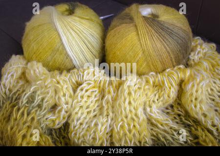 Palla in filato colorato sfumato con cardigan lavorato a maglia e aghi per maglieria. Fili di lana e alpaca color limone con splendidi motivi a maglia. Foto Stock