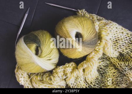 Palla in filato colorato sfumato con cardigan lavorato a maglia e aghi per maglieria. Fili di lana e alpaca color limone con splendidi motivi a maglia. Foto Stock