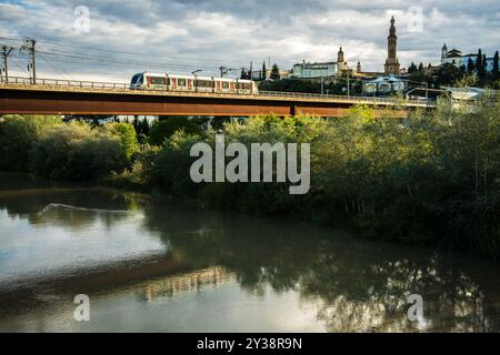 Una vista pittoresca del ponte della metropolitana che attraversa il fiume Guadalquivir a Siviglia, con San Juan de Aznalfarache sullo sfondo e lussureggiante vegetazione Foto Stock