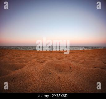 La piccolezza dell'uomo. Persona irriconoscibile in piedi sulla spiaggia di fronte al mare. Diminuire la prospettiva. Foto Stock